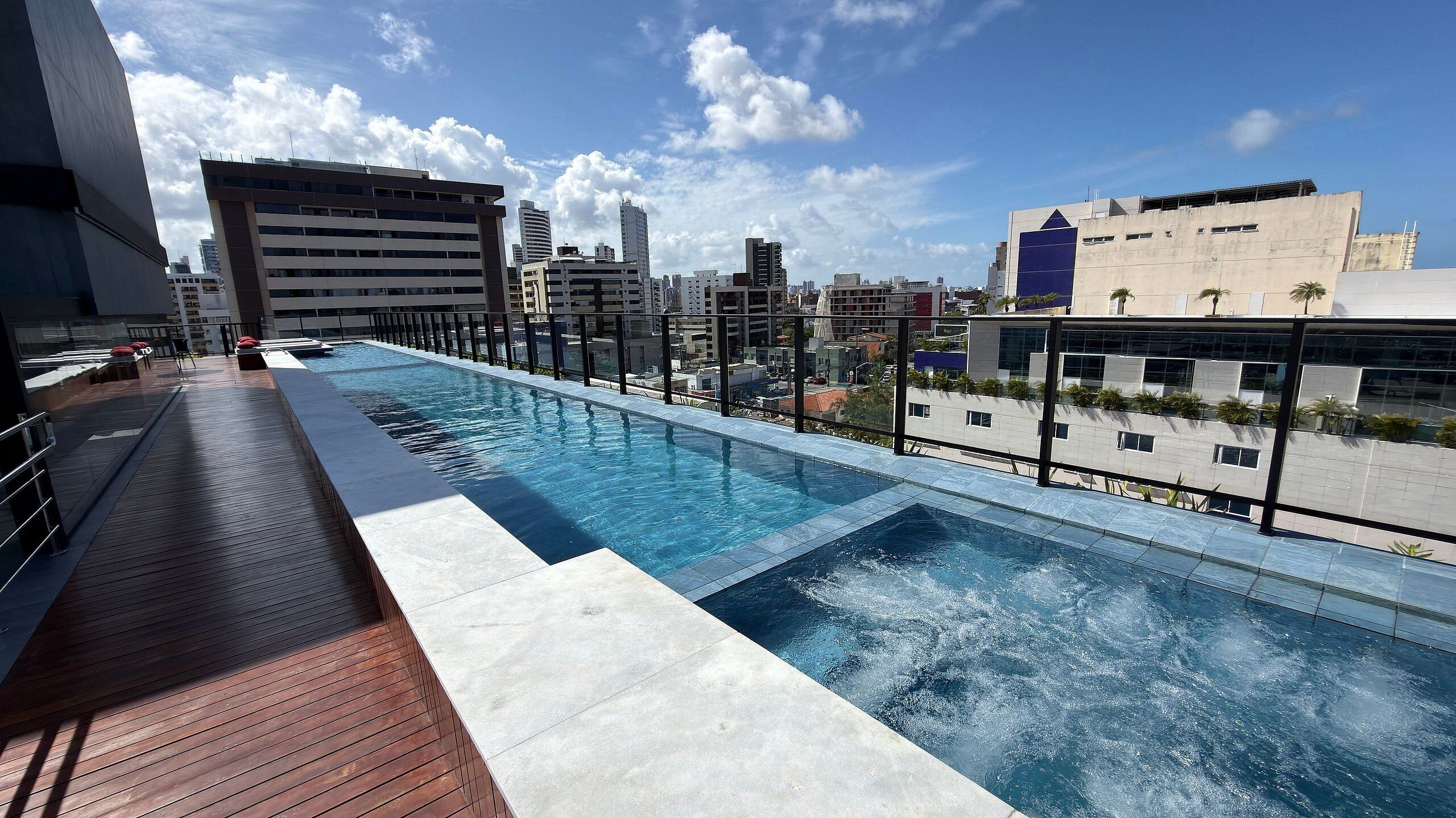 A rooftop infinity pool with a city view, surrounded by modern buildings.