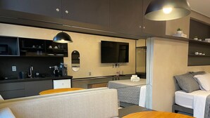 Un angolo cottura moderno con TV a schermo piatto, un piccolo frigorifero e una macchina del caffè.