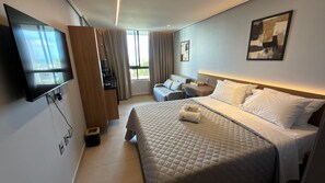Una camera d'albergo con un letto, una scrivania, una sedia, una TV e una finestra con tende.