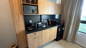 A compact kitchen with wooden cabinets, a black countertop, a sink, a coffee maker, and a dishwasher. - Luxury flat fully equipped at Acqua Tambau AQ4II (João Pessoa)