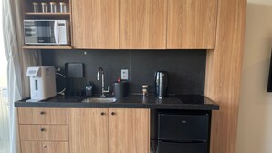 Eine kleine Küche mit Mikrowelle, Kaffeemaschine, Spüle und Kühlschrank.