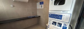 Un bagno con erogatore di gel disinfettante, dispenser di carta e manifesti informativi alle pareti.