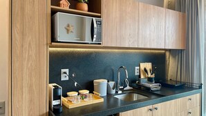 Eine moderne Küche mit Holzschränken, einer eingebauten Mikrowelle, einer Kaffeemaschine und einem Spülbecken.