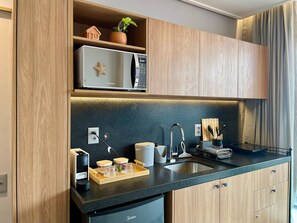 Eine moderne Küche mit Holzschränken, einer eingebauten Mikrowelle, einer Kaffeemaschine und einem Spülbecken.