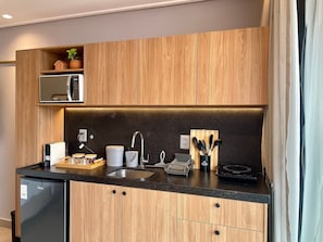 Eine moderne Küche mit Holzschränken, einer eingebauten Mikrowelle und einem Spülbecken.