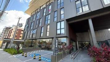 A modern building with a glass facade, a ramp leading to the entrance, and a parking area marked with a wheelchair symbol.