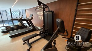 Ein Fitnessraum mit Laufbändern, einer Langhantelbank und einer Wand mit motivierenden Texten.