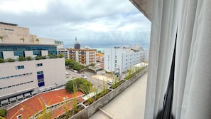 Vista desde una ventana con vista a un paisaje urbano con edificios, una carretera y un tejado de tejas rojas.