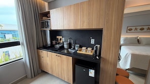 Una kitchenette compacta equipada con microondas, cafetera y refrigerador pequeño.