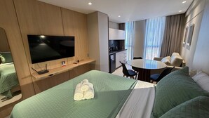 A hotel room with a bed, a TV, a dining table, and a kitchenette. - Luxury flat fully equipped at Acqua Tambau AQ2X7 (João Pessoa)
