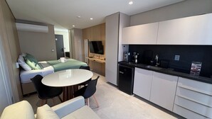 A compact hotel room with a bed, a small dining table, two chairs, a kitchenette, and a TV. - Luxury flat fully equipped at Acqua Tambau AQ2X7 (João Pessoa)