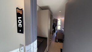 Un corridoio con una porta etichettata '301' che dà su una stanza con un letto e un tavolo.
