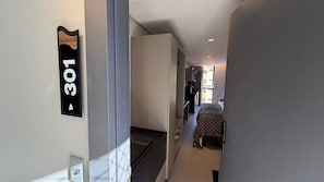 Un corridoio con una porta etichettata '301' che dà su una stanza con un letto e un tavolo.