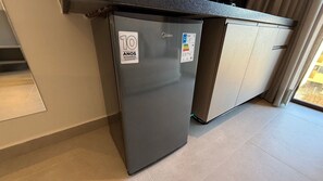 Una cucina compatta con un frigorifero grigio, un forno in acciaio inox e un forno a microonde integrato.