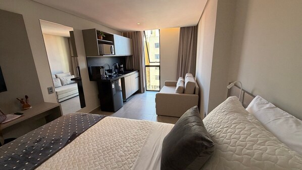 Camera d'albergo con un letto, una scrivania, angolo cottura e divano, con vista all'esterno.