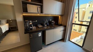 Un angolo cottura compatto con macchina da caffè, bollitore e forno a microonde.