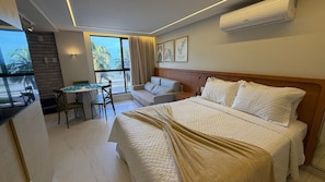 A hotel room with a bed, a desk, a chair, a sofa, and a window with curtains. - Apartment on the seafront of Cabo Branco UN204 (João Pessoa)