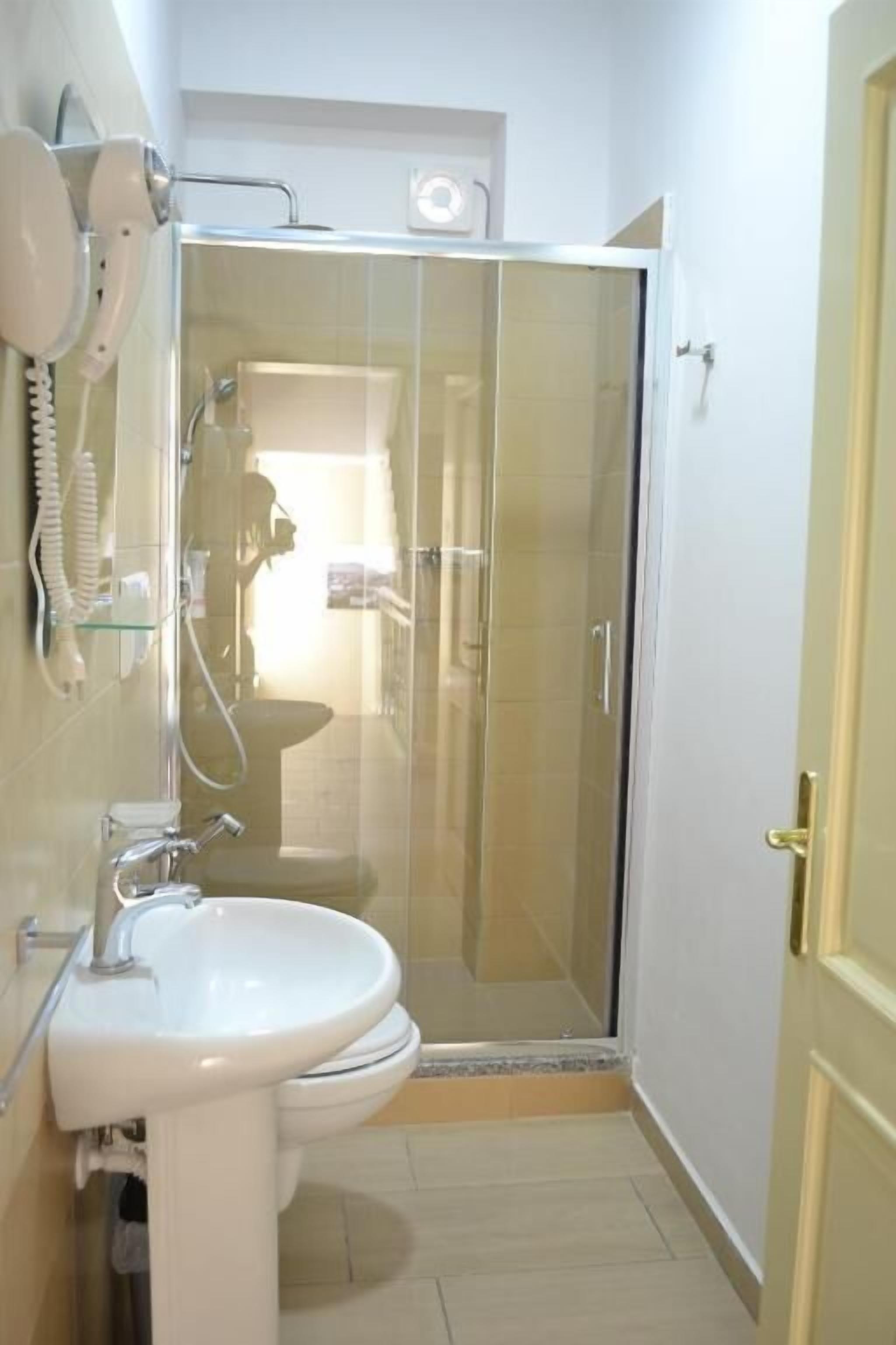 Un baño con cabina de ducha de vidrio, inodoro y lavamanos.