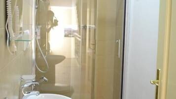 Un baño con cabina de ducha de vidrio, inodoro y lavamanos.