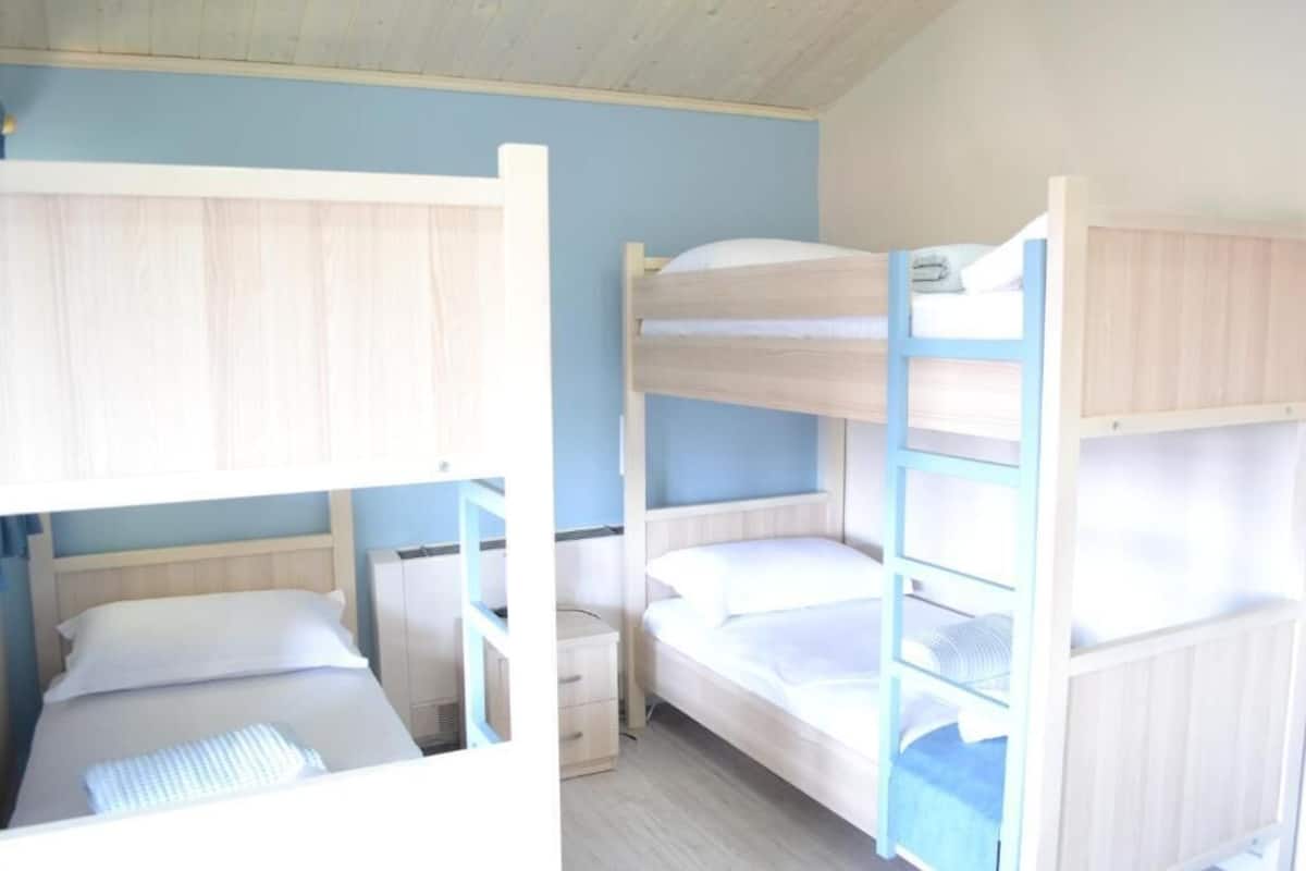 Una habitación con literas, una mesita de noche y otra mesita auxiliar.