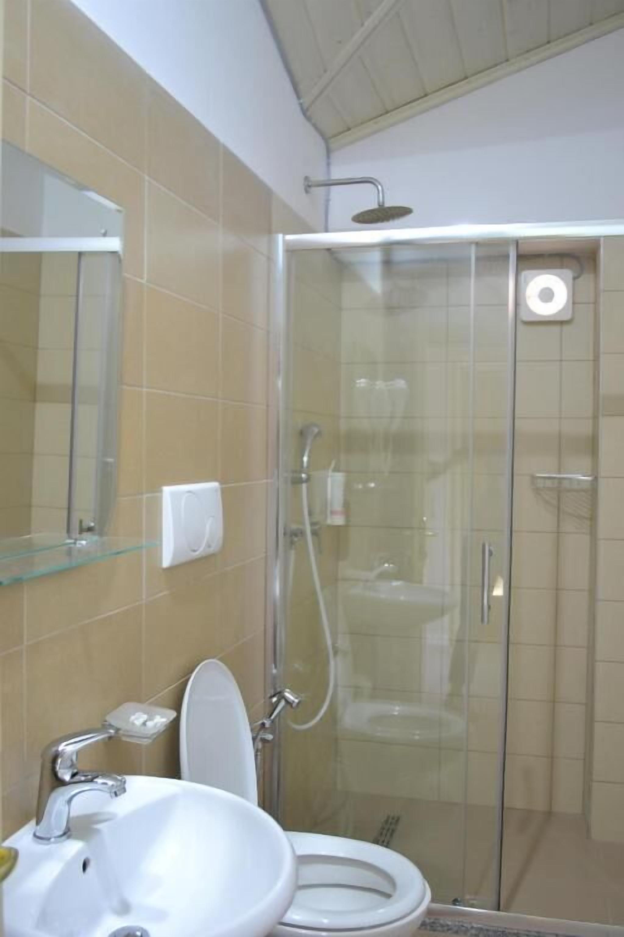 A bathroom with a glass-enclosed shower, a toilet, and a sink.