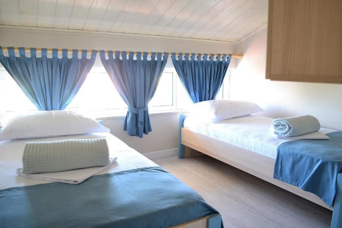 Una habitación con dos camas, techo de madera y cortinas.