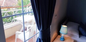 A balcony with a white table and chairs, a blue curtain, and a nightstand with a lamp. - Open Doors Bed & Breakfast  (Shkodër)