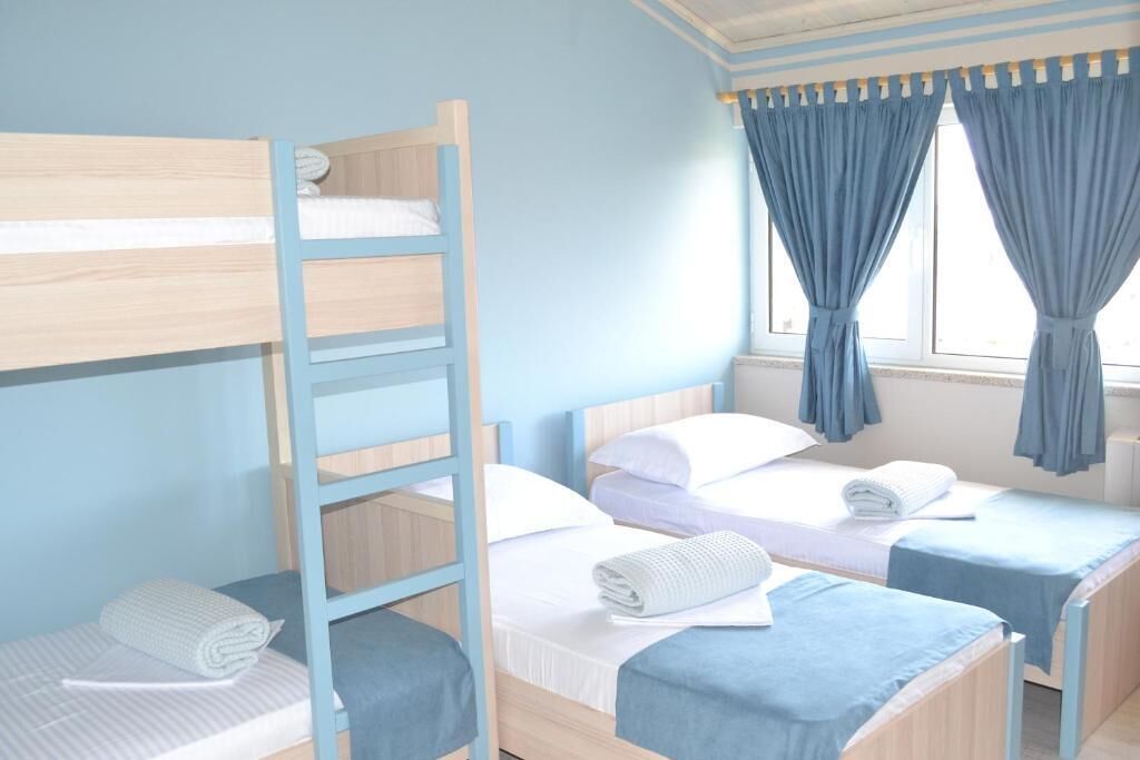 A room with bunk beds, a window with curtains, and a wooden ladder.