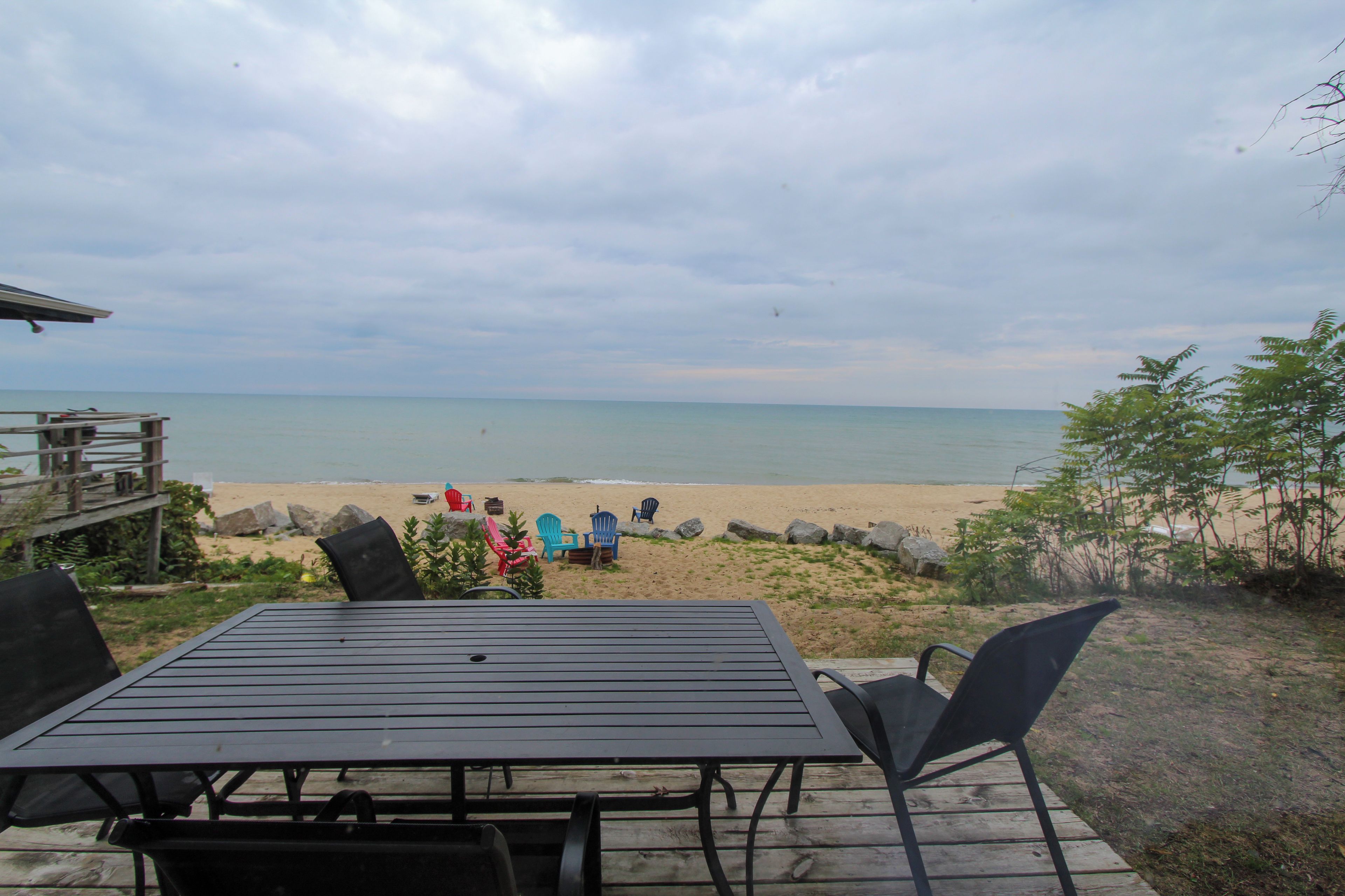 A deck with a table and chairs overlooking a beach.