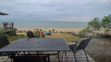 A deck with a table and chairs overlooking a beach.