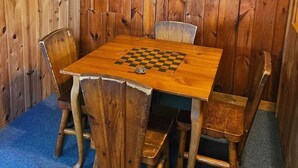 Una habitación de madera con una mesa de ajedrez y sillas, un cuadro en la pared y un techo de madera rústica.