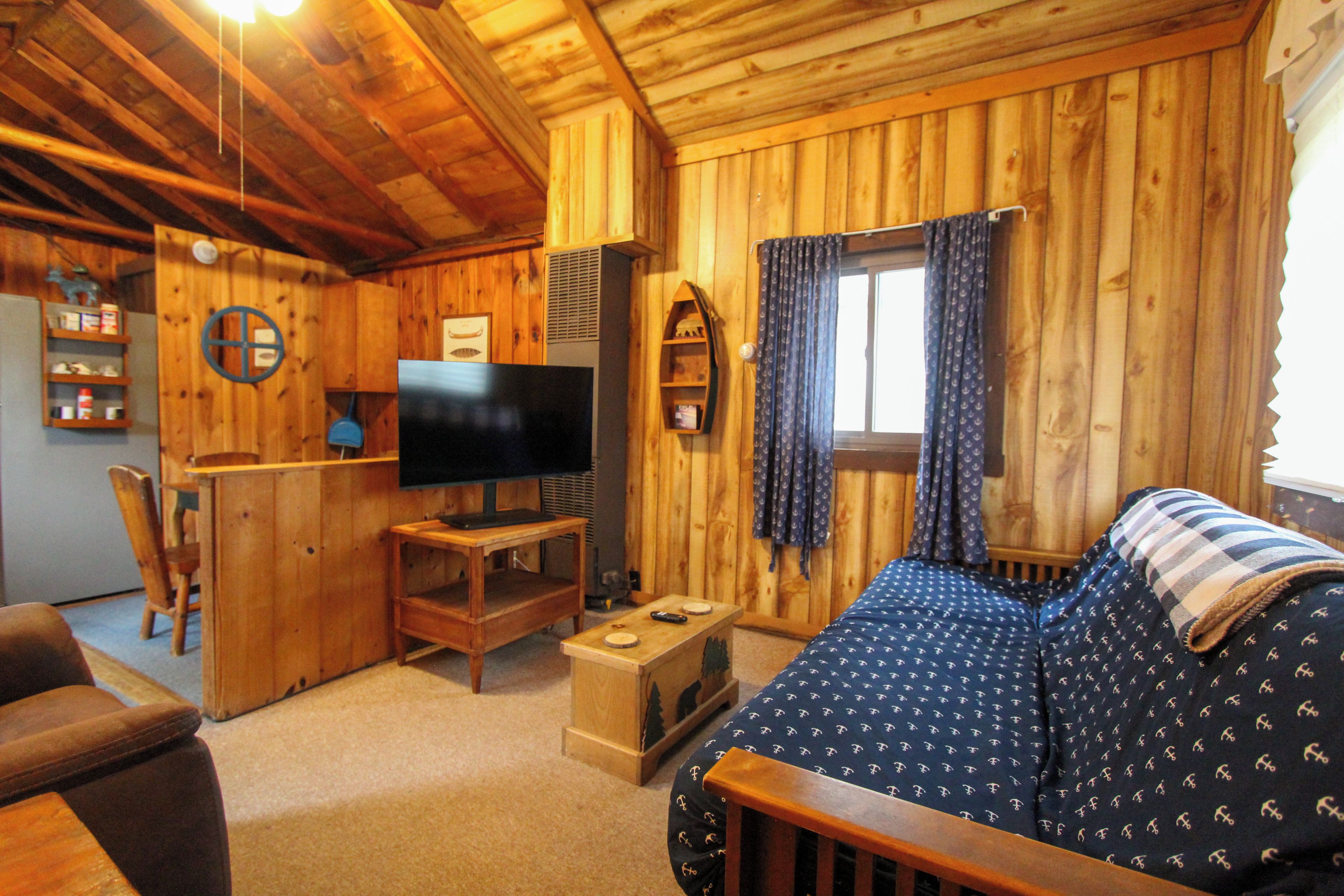 A wooden cabin interior with a sofa, television, and a small table.