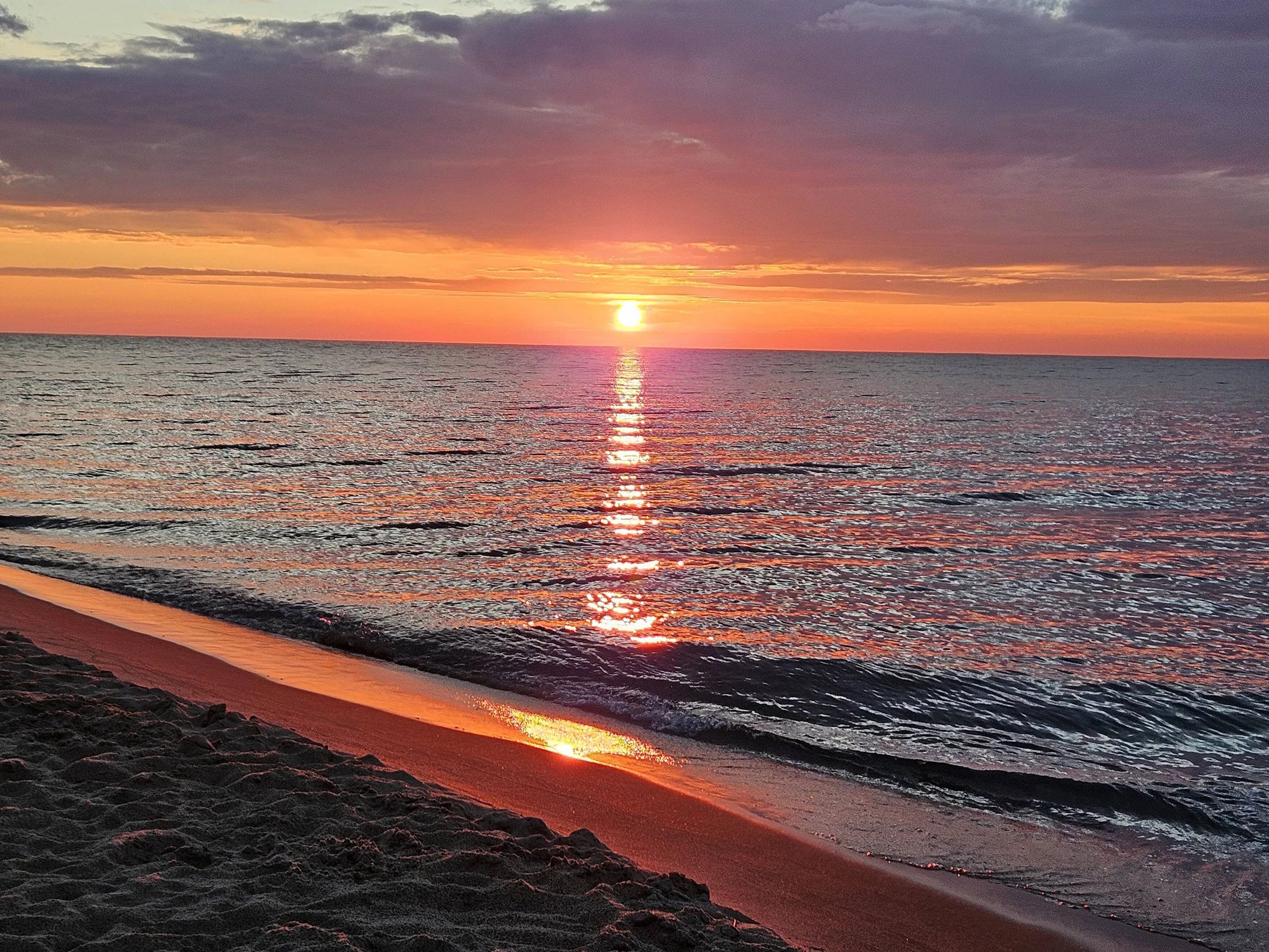 A beach with a sunset over the ocean.