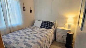 Un dormitorio con una cama, una mesita de noche, una lámpara y un reloj de pared.