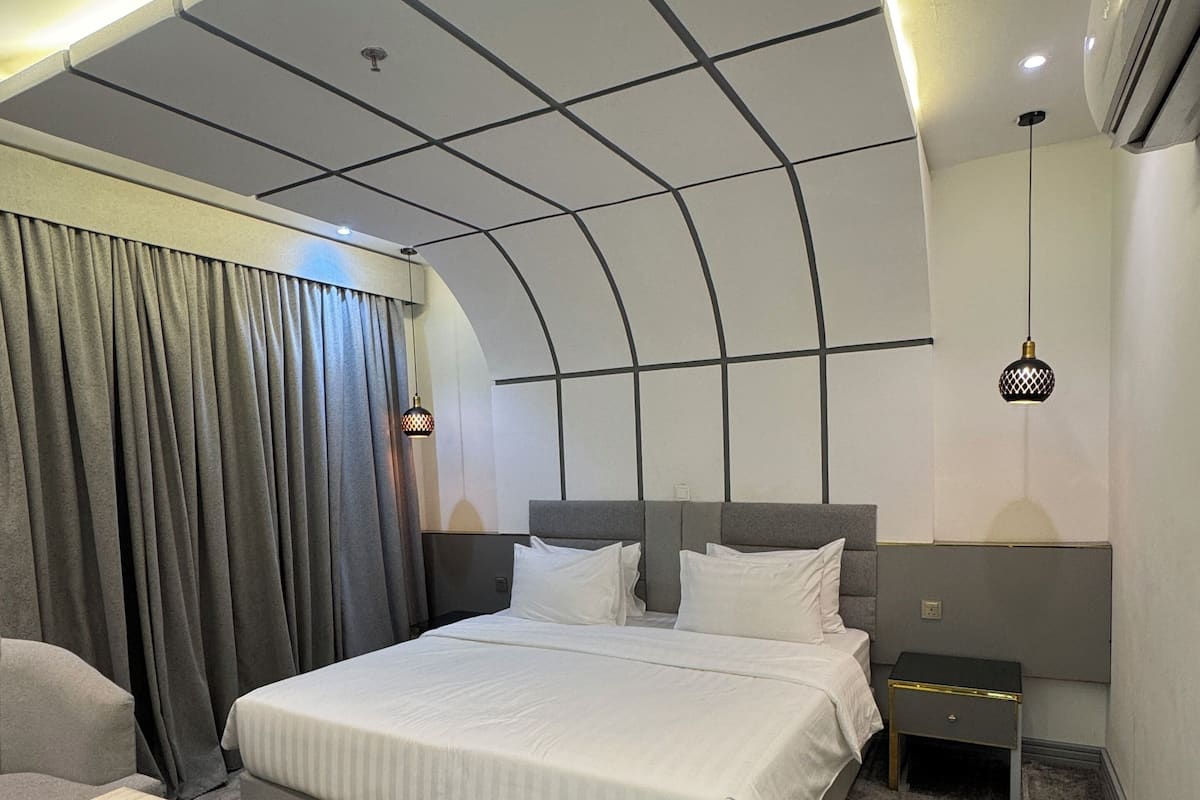 Una habitación de hotel moderna con una cama grande, una mesita de noche, una silla y un escritorio.