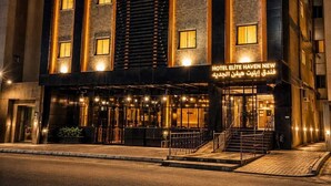 A multi-story hotel with a modern facade, illuminated windows, and a sign indicating it's a new hotel. - Elite Haven New Hotel (Madinah)