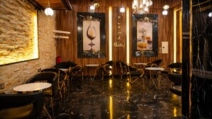 Ein Restaurantinnenraum mit Holzwänden, Marmorböden und verschiedenen Sitzgelegenheiten, darunter runde Tische und Stühle.