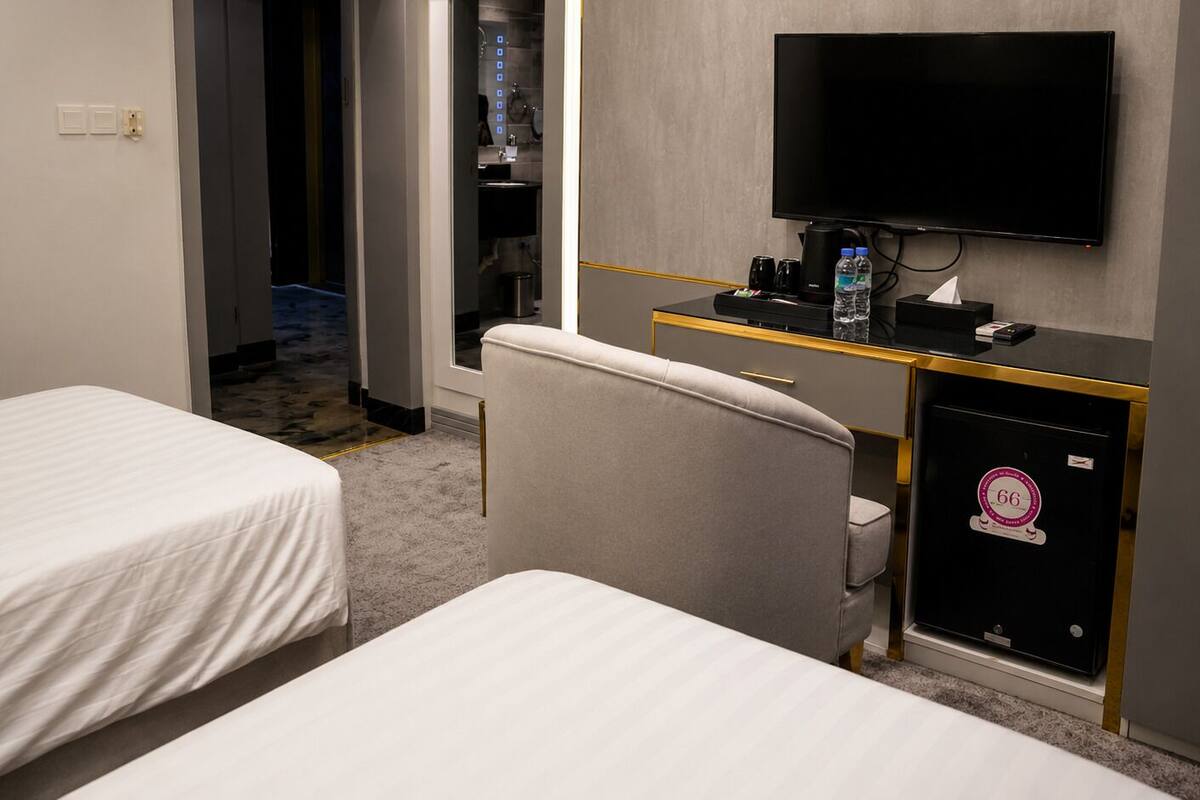 Habitación de hotel con dos camas, un escritorio, televisión de pantalla plana, una silla, un minibar y una puerta que da a un baño.