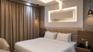 Ein modernes Hotelzimmer mit einem großen Bett, einem Nachttisch, einem Sessel und einer Wandleuchte.