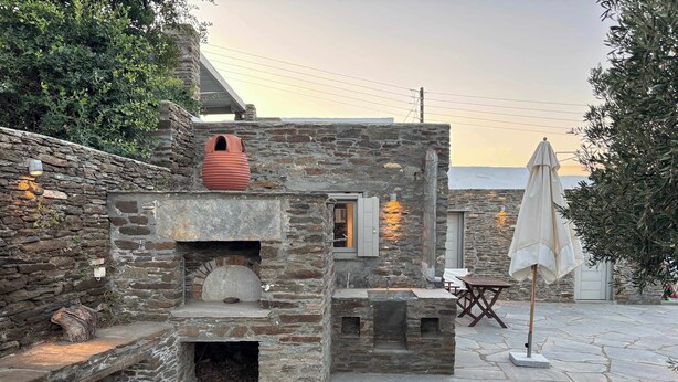A stone building with a fireplace, outdoor seating, and a pergola. - #HH11 Guestroom for two in Katavati (Sifnos)