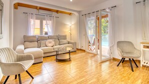A living room with a sofa, chairs, a coffee table, and a sliding glass door leading to an outdoor area. - 4BR Wellness Villa | Pool, Sauna, Gym (Puerto de la Cruz)
