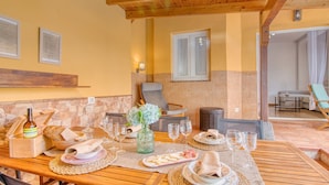 A dining area with a wooden table set for a meal, a wicker chair, and a wicker sofa. - 4BR Wellness Villa | Pool, Sauna, Gym (Puerto de la Cruz)