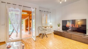 A modern living room with a large flat-screen TV, a glass coffee table, and a sliding glass door leading to an outdoor area. - 4BR Wellness Villa | Pool, Sauna, Gym (Puerto de la Cruz)