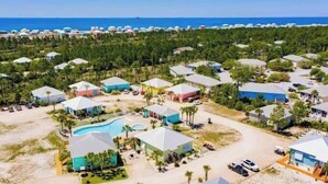 Luchtbeeld van een resort met meerdere gebouwen, een centraal zwembad en een strand op de achtergrond.