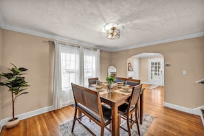 A dining room with a wooden table set for four, a potted plant, and a ceiling fan. - Classic Tudor Getaway |Fireplace|Parking|Workspace (South Euclid)