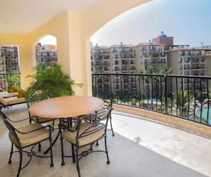 Ein Balkon mit rundem Tisch und Stühlen, einem Blumentopf und Blick auf ein Wohngebiet mit Gebäuden.