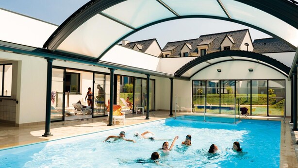 An indoor swimming pool with a glass ceiling, surrounded by a covered patio area. - Family Cottage for 8 in Morbihan (Queven)