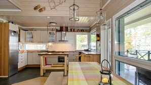 Una cocina moderna con armarios de madera, un refrigerador de acero inoxidable, una mesa de comedor de madera con mantel colorido y un farol colgante.