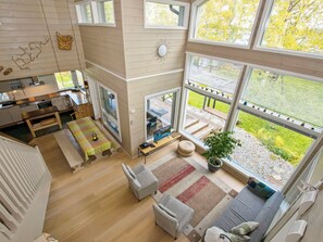 A spacious living area with a large window, a dining table, and a cozy seating arrangement.