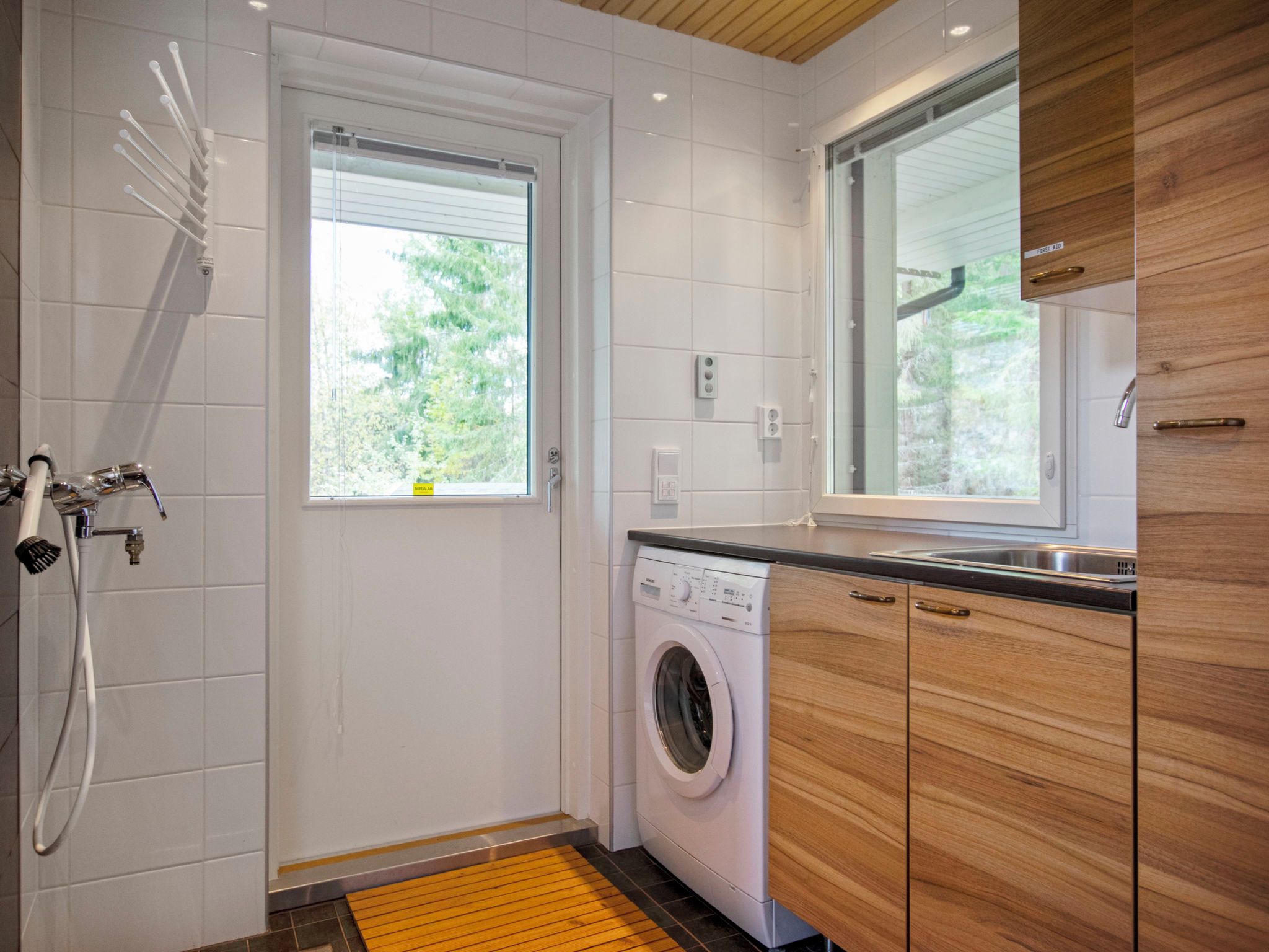 Une petite salle de bain équipée d’une douche, d’un lave-linge et d’un lavabo.